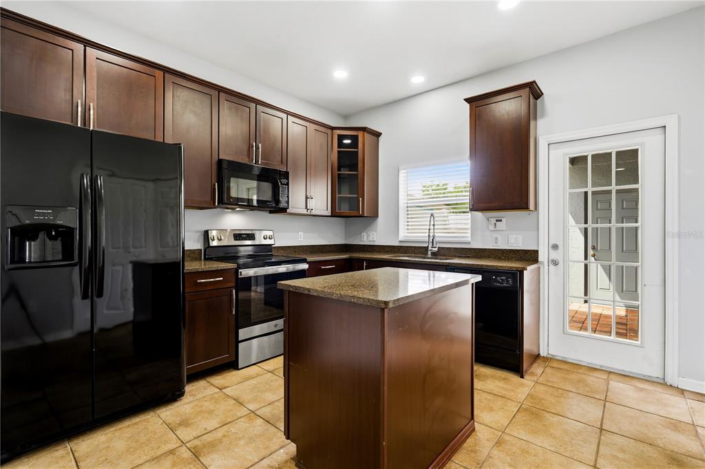 A kitchen with dark wood cabinets, granite countertops, a center island, and stainless steel appliances — 6364 LAKE SMITH CIRCLE, WINDERMERE, FL
