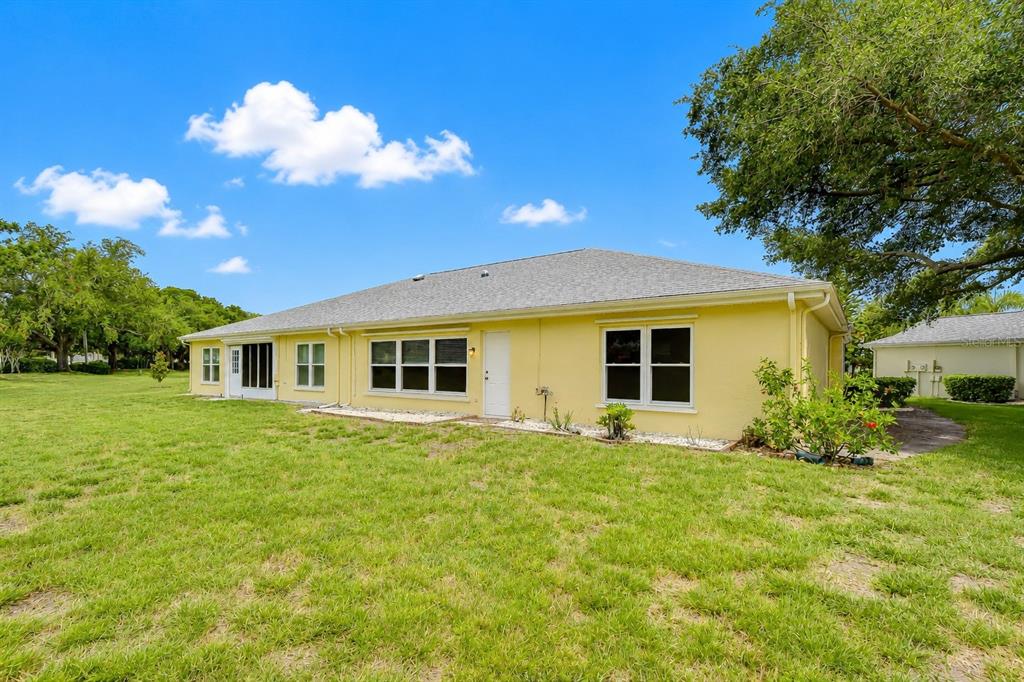 A yellow single-story house with a gray shingled roof sits on a grassy lawn — 818 MCCALLISTER AVENUE, SUN CITY CENTER, FL