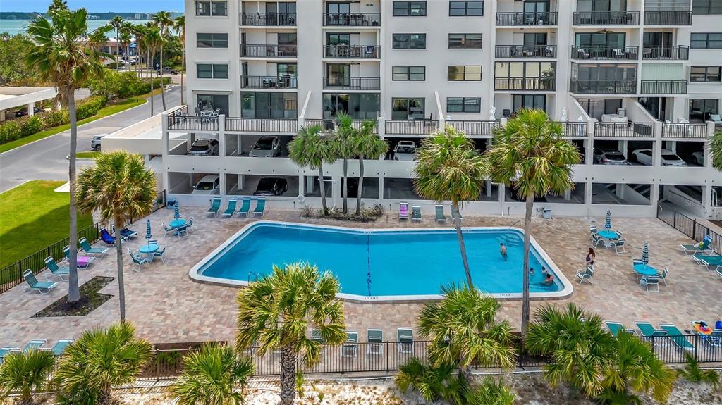 An aerial view of a multi-story apartment building with a swimming pool and palm trees — 1270 GULF BOULEVARD UNIT 1501, CLEARWATER BEACH, FL