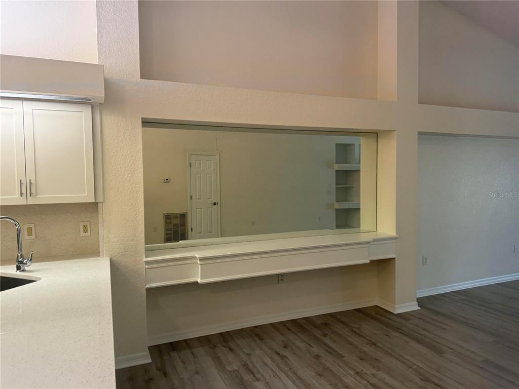 A kitchen area features a large wall mirror above a white shelf and wood flooring — 9443 BURNAM DRIVE, WEEKI WACHEE, FL