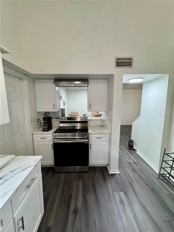 A kitchen features white cabinets, stainless steel appliances, and dark wood-look flooring — 12315 TOUCHTON DRIVE UNIT 90, TAMPA, FL