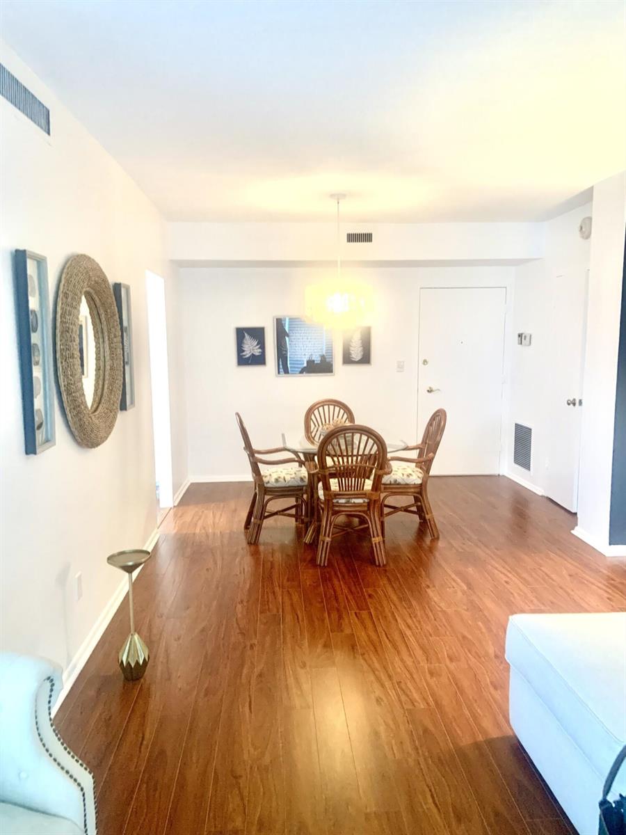 A dining area with a glass-topped rattan table set on dark wood flooring — 2840 S Ocean Boulevard # 2050, Palm Beach FL 33480, PALM BEACH, FL