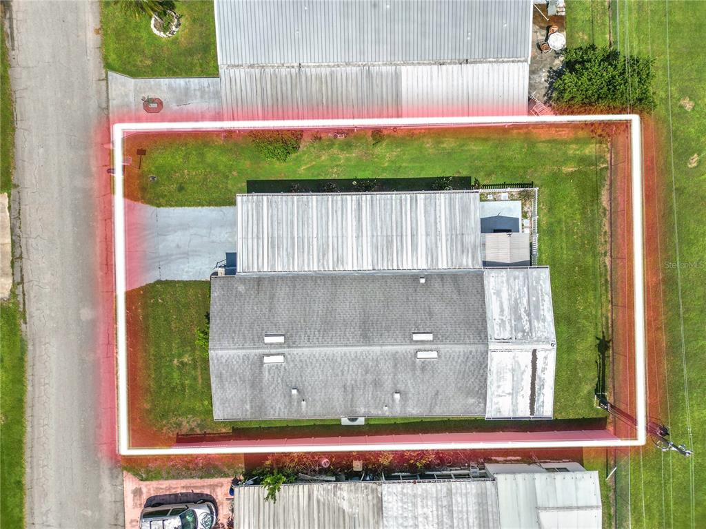 An aerial view shows a house with a metal roof and a fenced-in yard — 3562 LAZY LAKE DRIVE N, LAKELAND, FL
