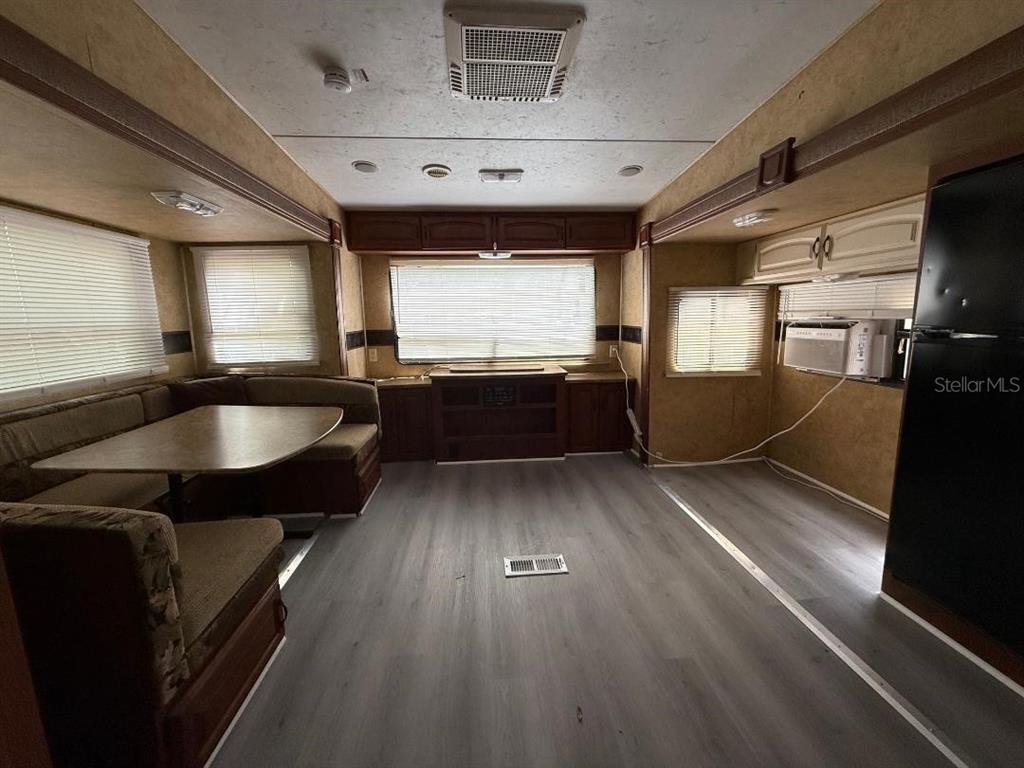 An interior view of a travel trailer featuring a dining booth, wood cabinetry, and flooring — 3000 CLARCONA ROAD UNIT 554, APOPKA, FL