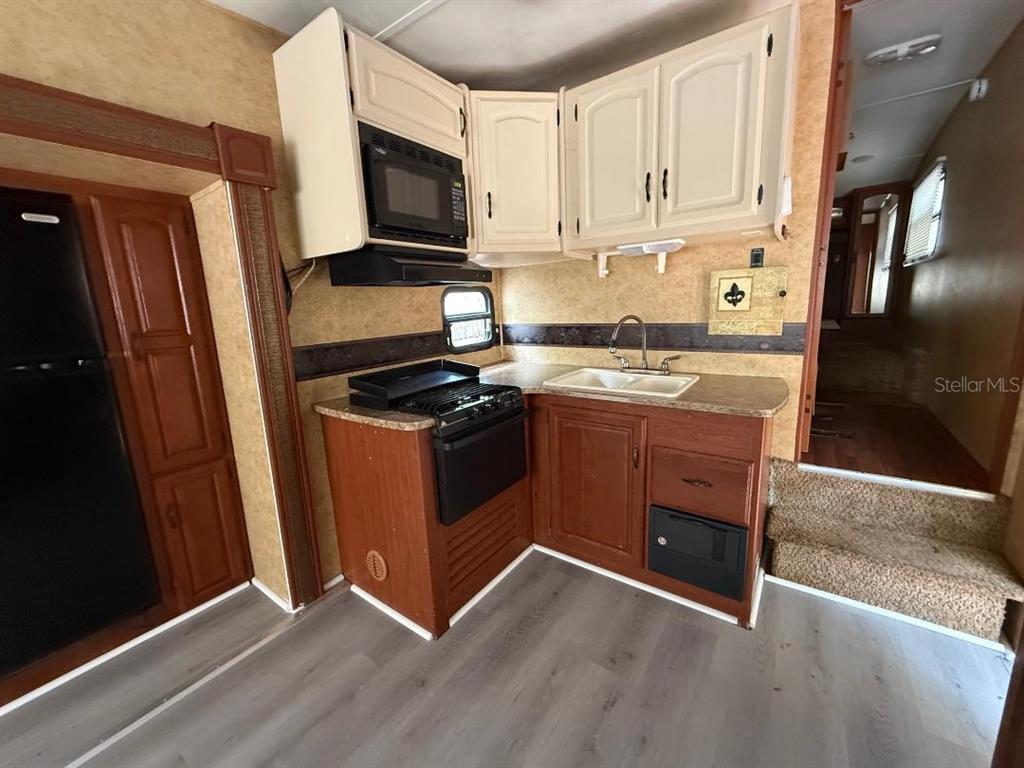 A kitchen in a recreational vehicle features wood cabinets, a stove, and a sink — 3000 CLARCONA ROAD UNIT 554, APOPKA, FL