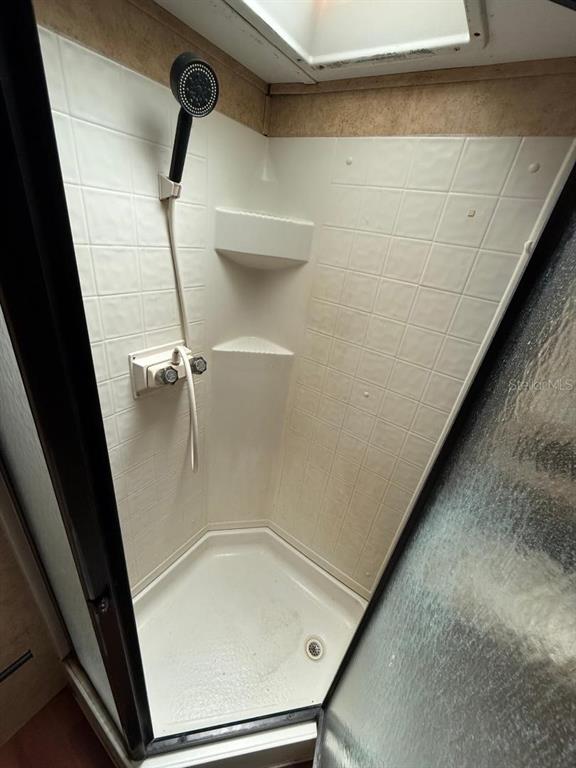 A corner shower stall features white tiled walls, a handheld showerhead, and a glass door — 3000 CLARCONA ROAD UNIT 554, APOPKA, FL