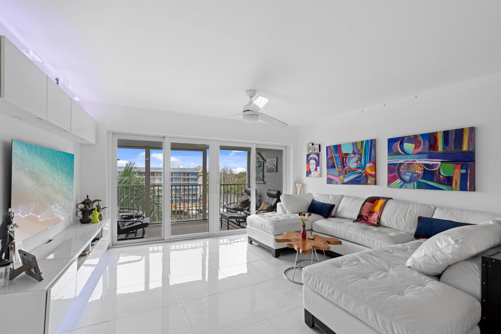 A bright living room features white tile floors, a white sectional sofa, and sliding glass doors — 1523 E Hillsboro Boulevard # 634, Deerfield Beach FL 33441, DEERFIELD BEACH, FL