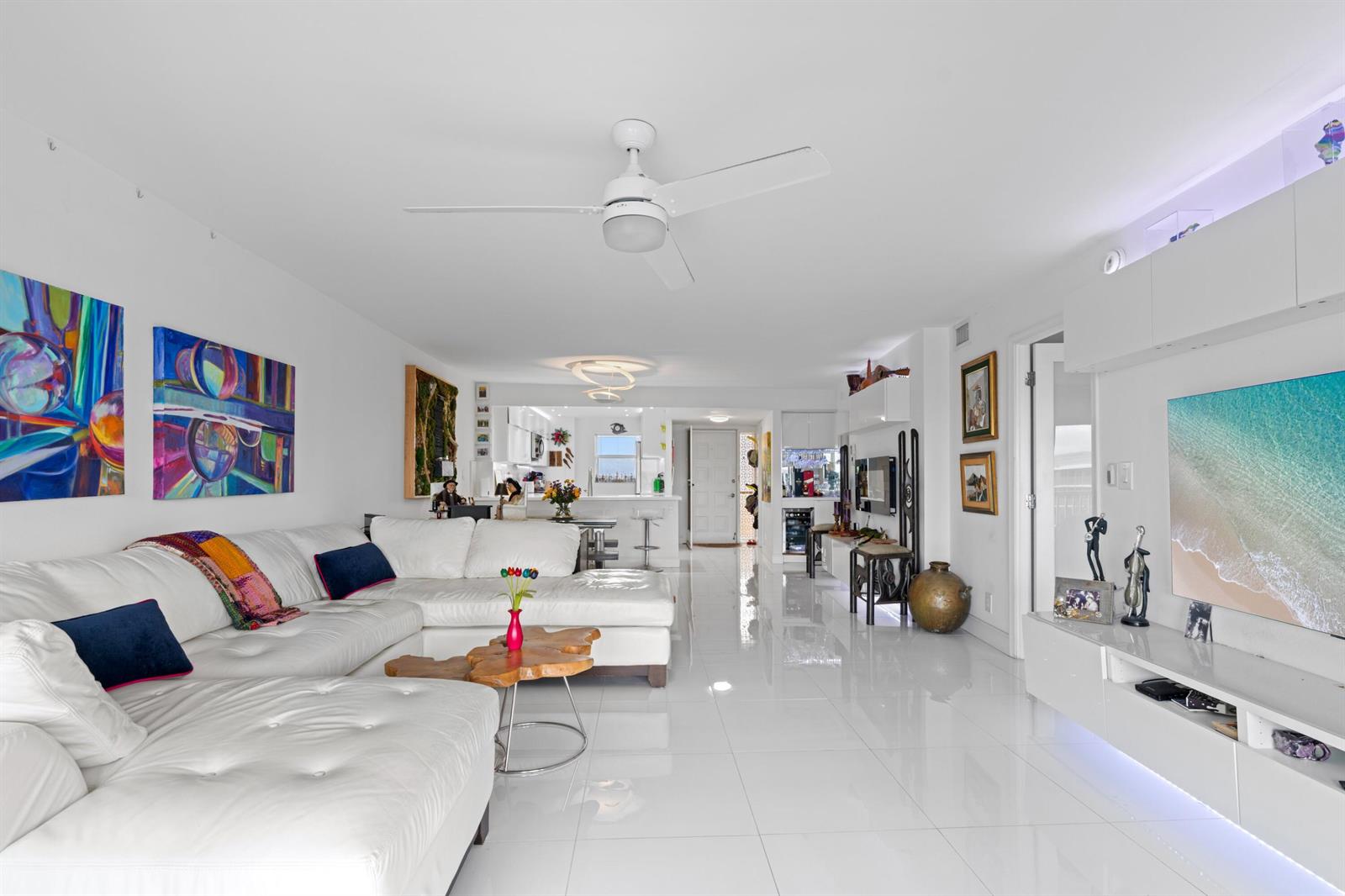 A bright, open-concept living room features white tile floors, a sectional sofa, and a television — 1523 E Hillsboro Boulevard # 634, Deerfield Beach FL 33441, DEERFIELD BEACH, FL