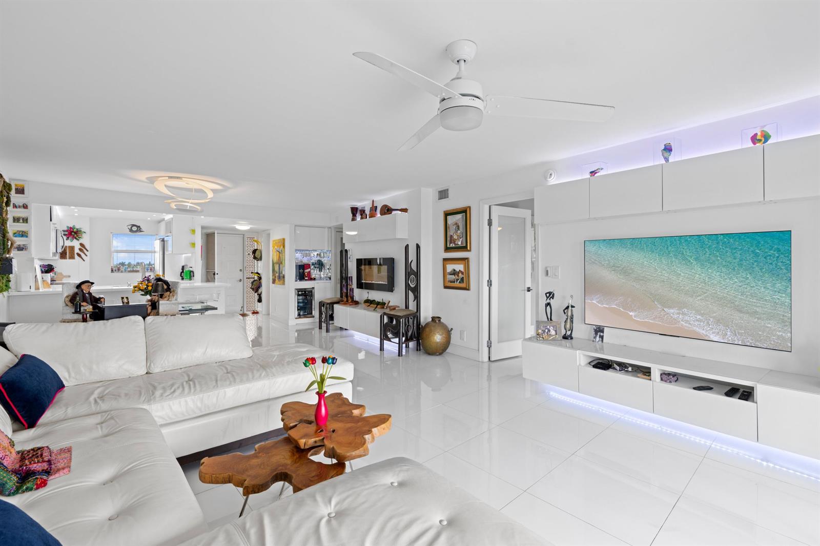 A bright living room features white tile floors, a sectional sofa, and a wall-mounted television — 1523 E Hillsboro Boulevard # 634, Deerfield Beach FL 33441, DEERFIELD BEACH, FL