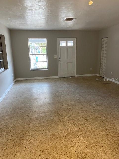 A living room features light gray walls, a window, a white door, and terrazzo flooring — 6442 TREEHAVEN DRIVE, SPRING HILL, FL