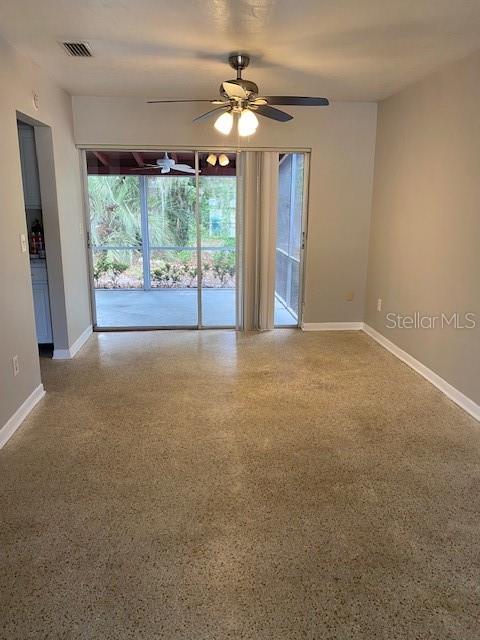 A dining area with a ceiling fan, sliding glass doors, and speckled concrete flooring — 6442 TREEHAVEN DRIVE, SPRING HILL, FL