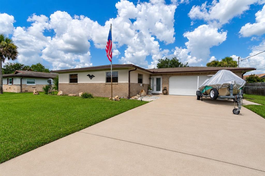 A single-story brick house with a concrete driveway and a boat on a trailer — 103 DEE STREET, NEW SMYRNA BEACH, FL