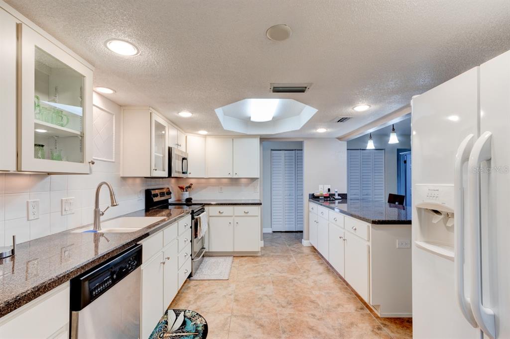A kitchen with white cabinets, granite countertops, tile flooring, and a central skylight — 103 DEE STREET, NEW SMYRNA BEACH, FL