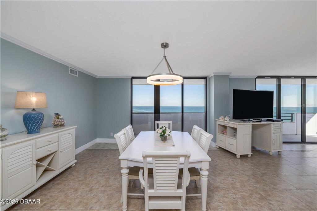 A dining area features a white table, chairs, and a view of the ocean — 1420 N ATLANTIC AVENUE UNIT 1601, DAYTONA BEACH, FL