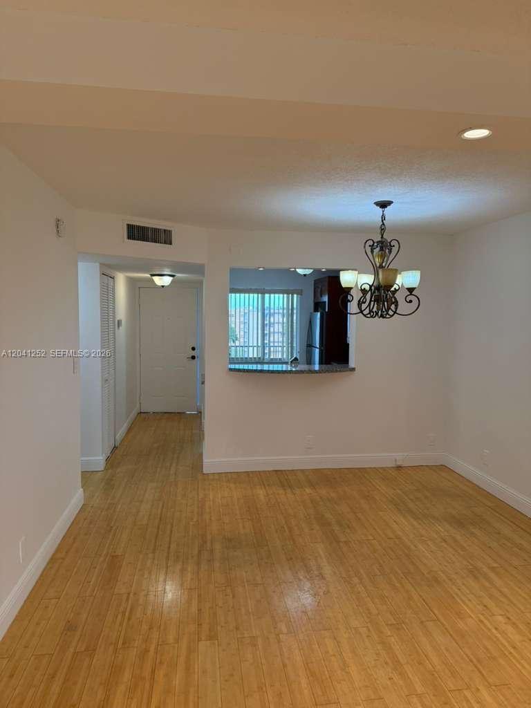 This dining area features light wood flooring, a chandelier, and a pass-through to the kitchen — 8610 N Sherman Cir # 508, Miramar FL 33025, MIRAMAR, FL