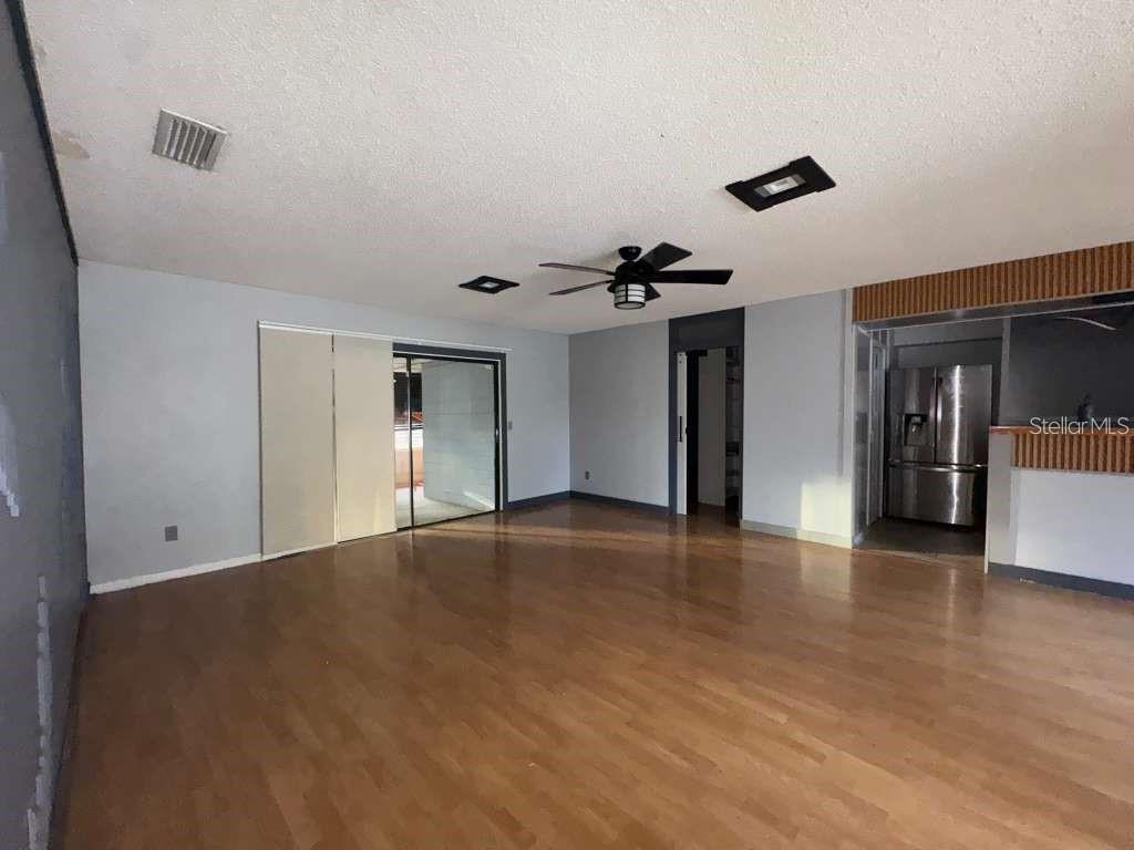 An open living area with wood flooring, a ceiling fan, and a kitchen view — 15906 COUNTRY FARM PLACE, TAMPA, FL