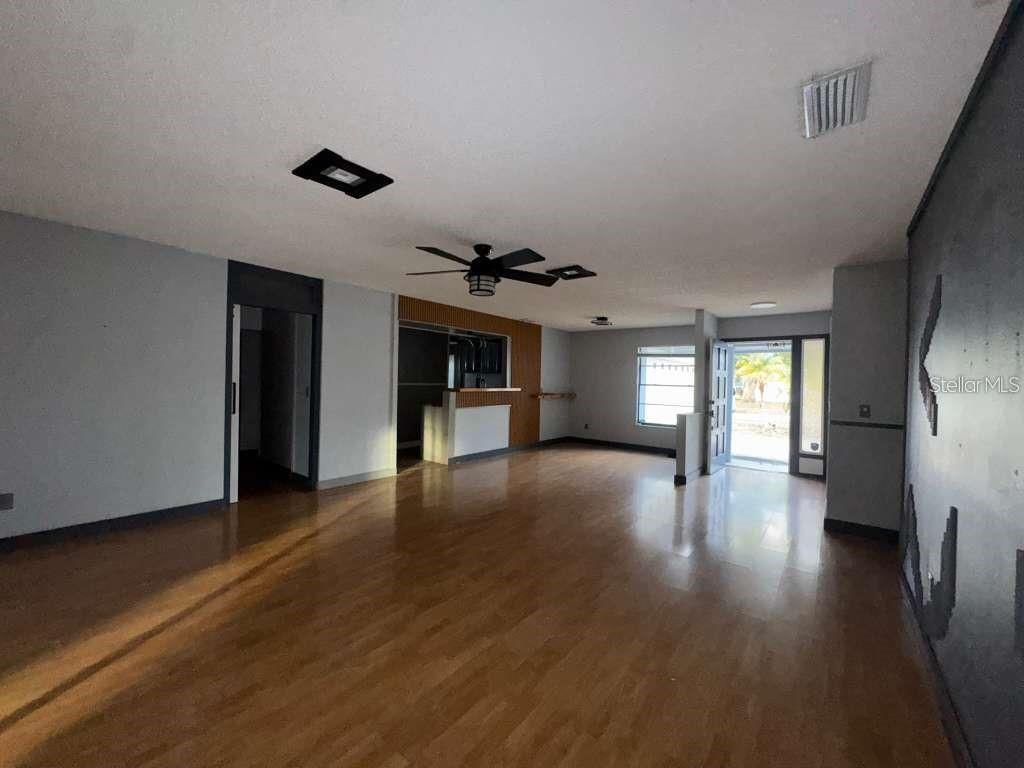An open-concept living area features wood flooring, a ceiling fan, and a kitchen pass-through window — 15906 COUNTRY FARM PLACE, TAMPA, FL