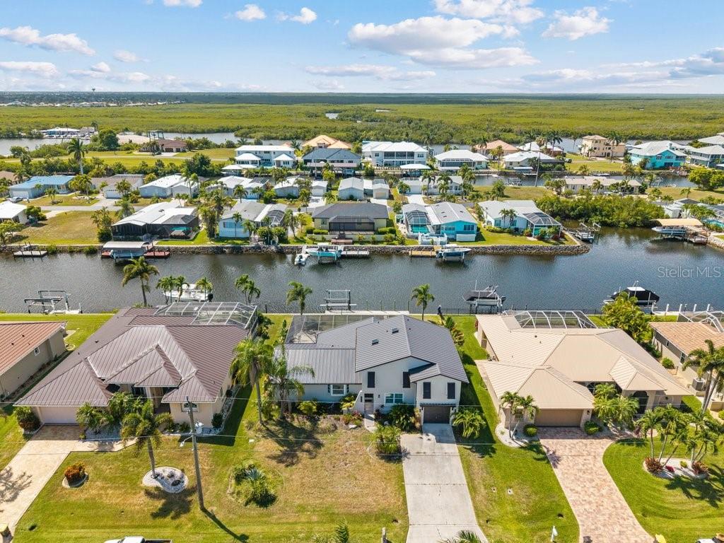 An aerial view shows waterfront houses with boat docks along a canal near marshland — 5400 ALMAR DRIVE, PUNTA GORDA, FL