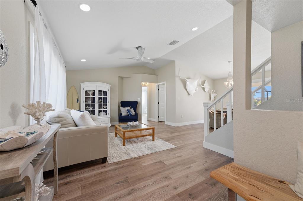 A living room features light wood flooring, a white sofa, and a blue armchair — 5400 ALMAR DRIVE, PUNTA GORDA, FL
