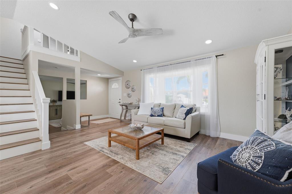 A living room features wood-look flooring, a staircase, a ceiling fan, and a beige sofa — 5400 ALMAR DRIVE, PUNTA GORDA, FL