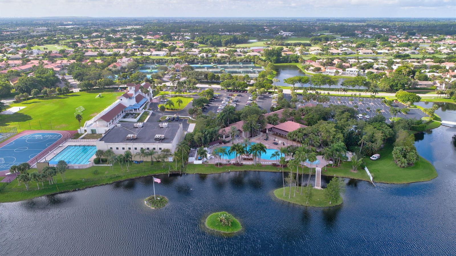 An aerial view shows a community clubhouse with a pool, sports courts, and a lake — 11038 Baybreeze Way, Boca Raton FL 33428, BOCA RATON, FL