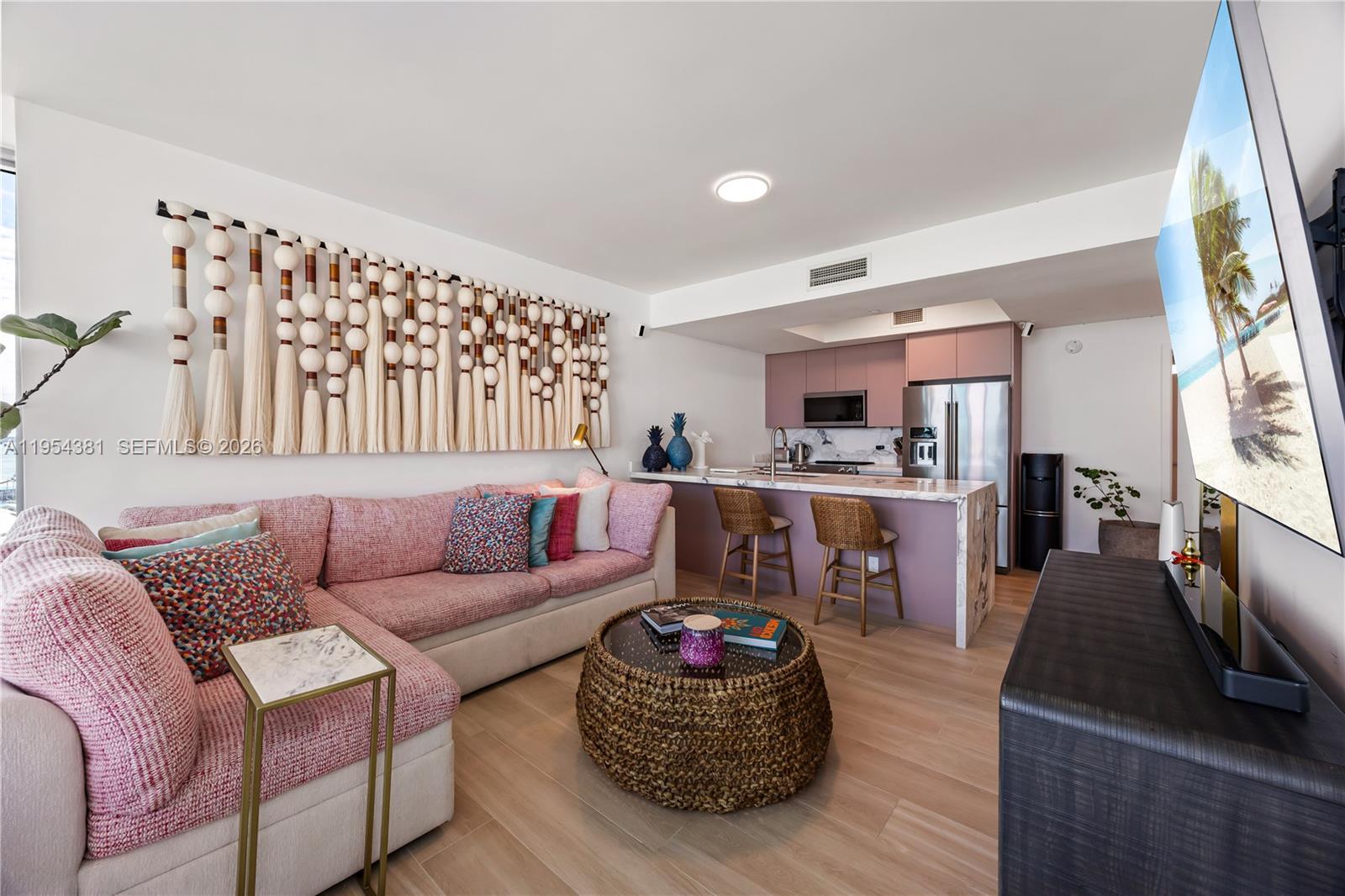 A living room with a pink sectional sofa, a woven coffee table, and an open kitchen — 888 Biscayne Blvd # 2009, Miami FL 33132, MIAMI, FL
