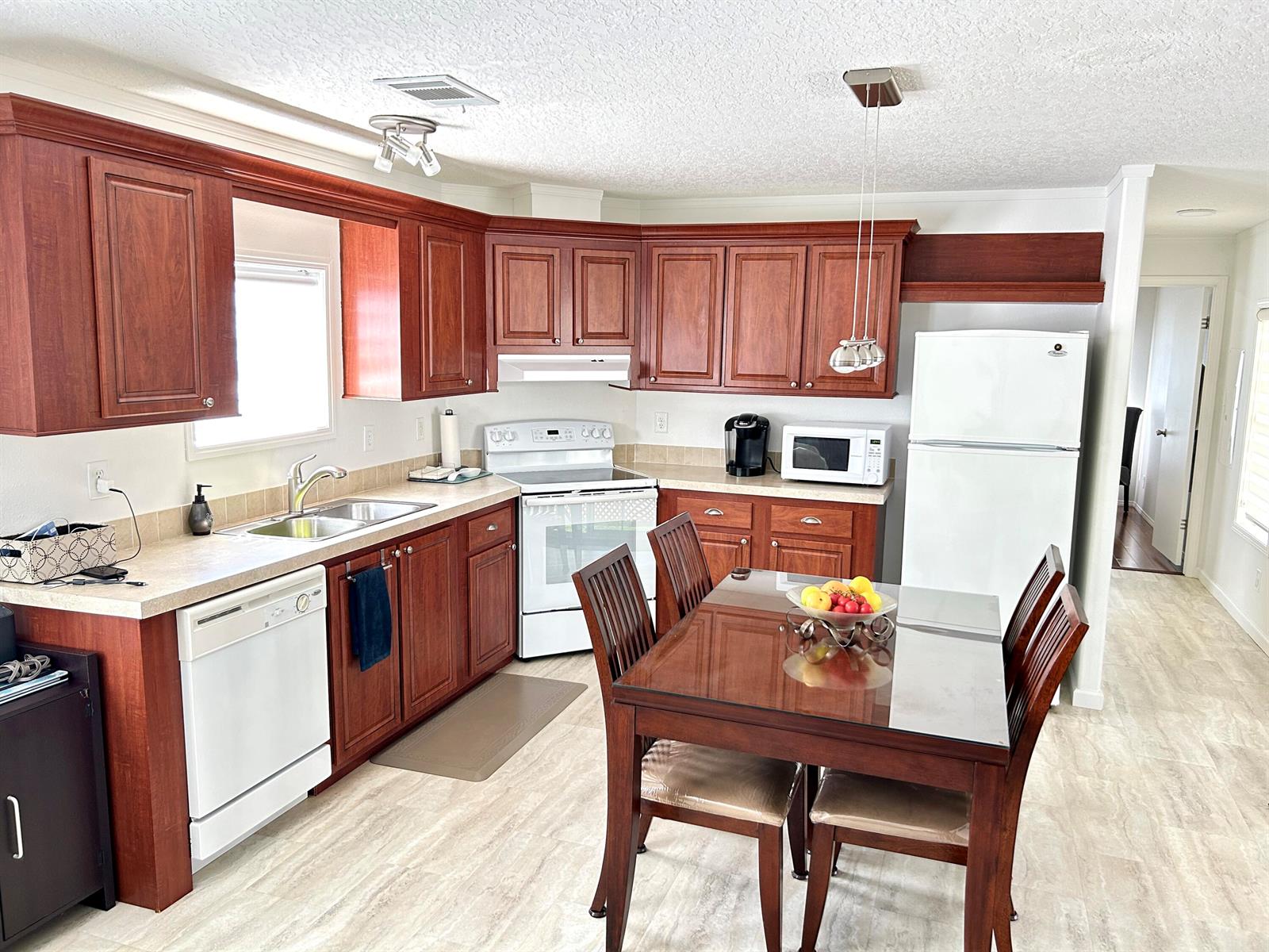 A kitchen features cherry wood cabinets, white appliances, a glass-top dining table, and light flooring — 613 Jasmine Lane, Deerfield Beach FL 33442, DEERFIELD BEACH, FL