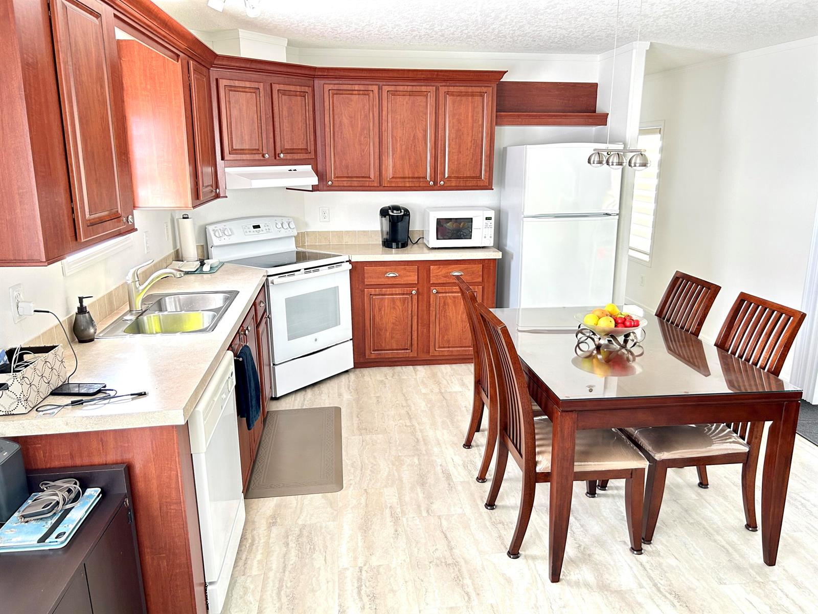 A kitchen features wood cabinets, white appliances, a dining table, and light-colored flooring — 613 Jasmine Lane, Deerfield Beach FL 33442, DEERFIELD BEACH, FL