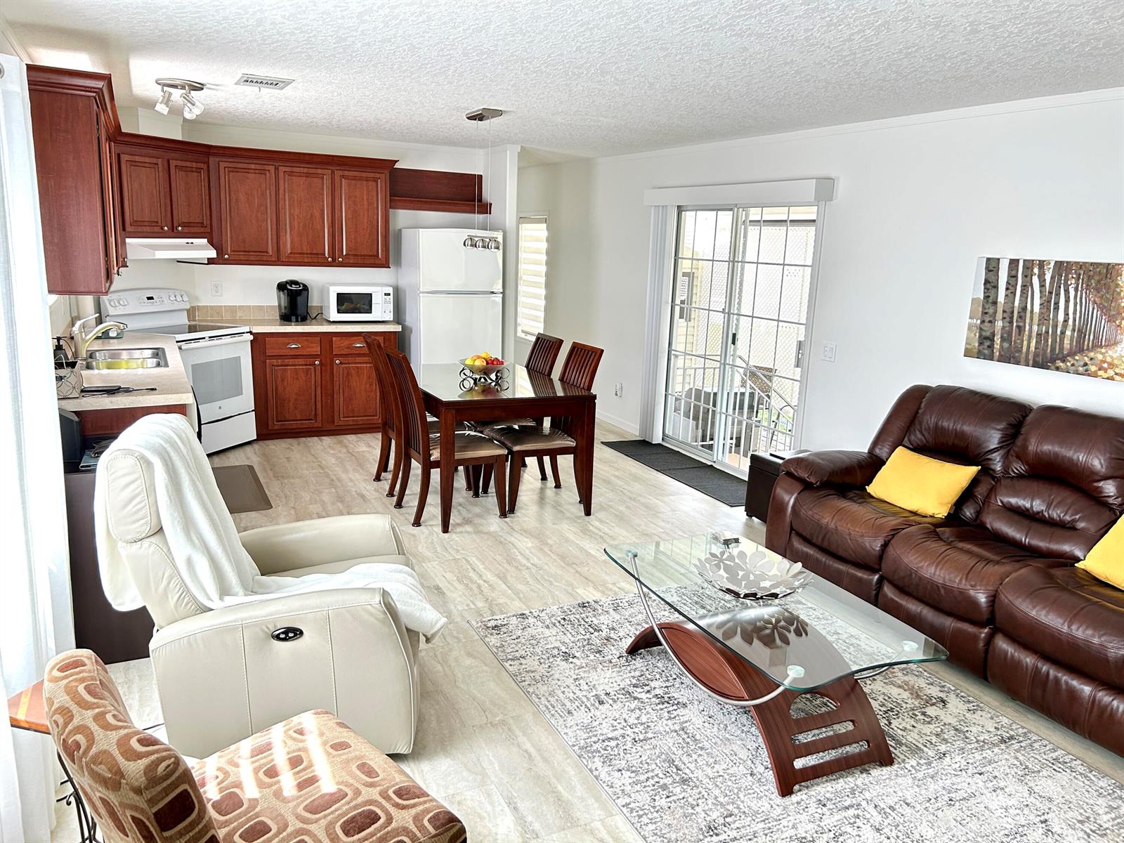 An open-concept living and dining area features dark wood cabinets, leather furniture, and tile flooring — 613 Jasmine Lane, Deerfield Beach FL 33442, DEERFIELD BEACH, FL