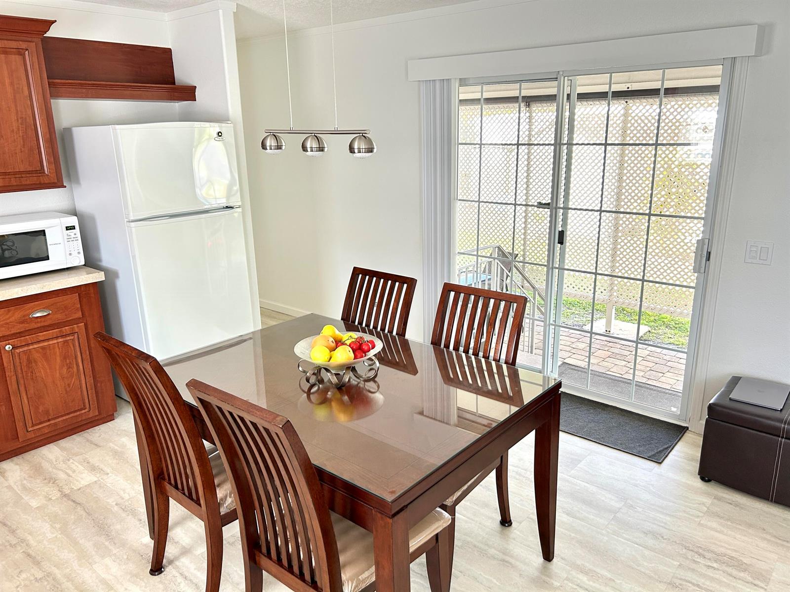 A dining area features a glass-topped table, wooden chairs, and a sliding glass door — 613 Jasmine Lane, Deerfield Beach FL 33442, DEERFIELD BEACH, FL