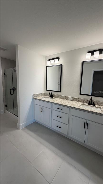 A bathroom features a double vanity with white cabinets, granite countertops, and a glass-enclosed shower — 2683 AVERLAND LOOP, NORTH PORT, FL