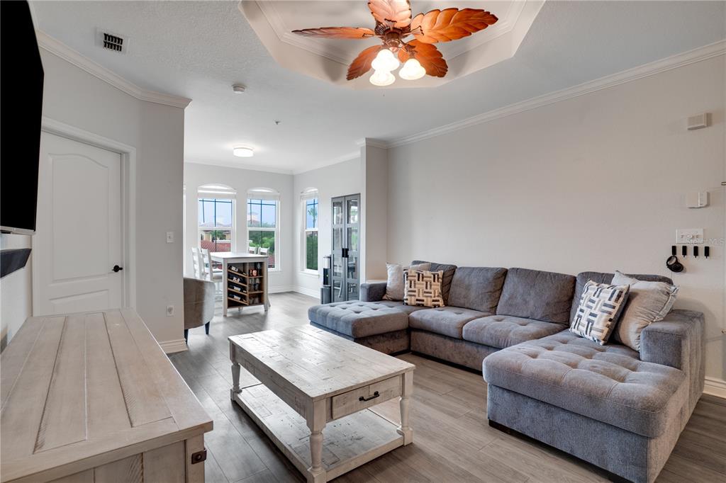 A living room with a gray sectional sofa, wooden coffee table, and a ceiling fan — 2705 VIA MURANO UNIT 131, CLEARWATER, FL