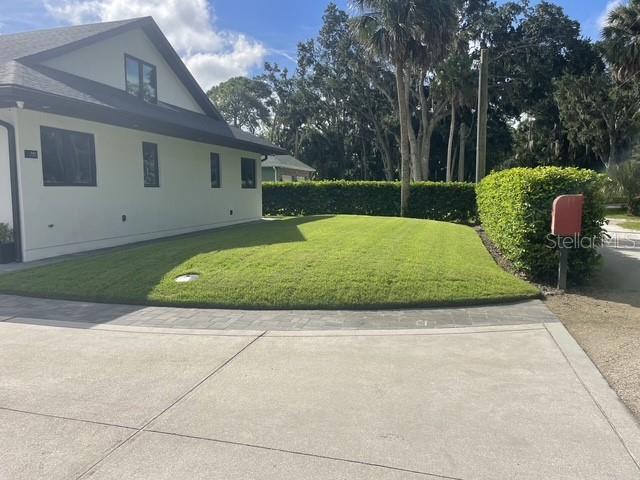 A white house with a dark roof sits next to a manicured lawn and hedge — 995 STACY LANE, NEW SMYRNA BEACH, FL