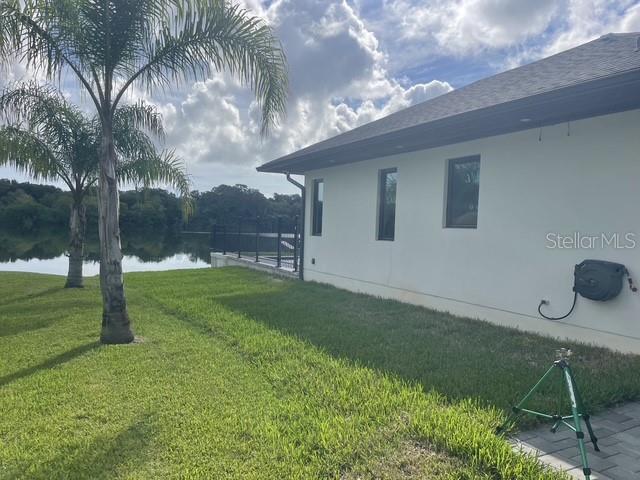 A palm tree stands on a lawn beside a white house with a water view — 995 STACY LANE, NEW SMYRNA BEACH, FL