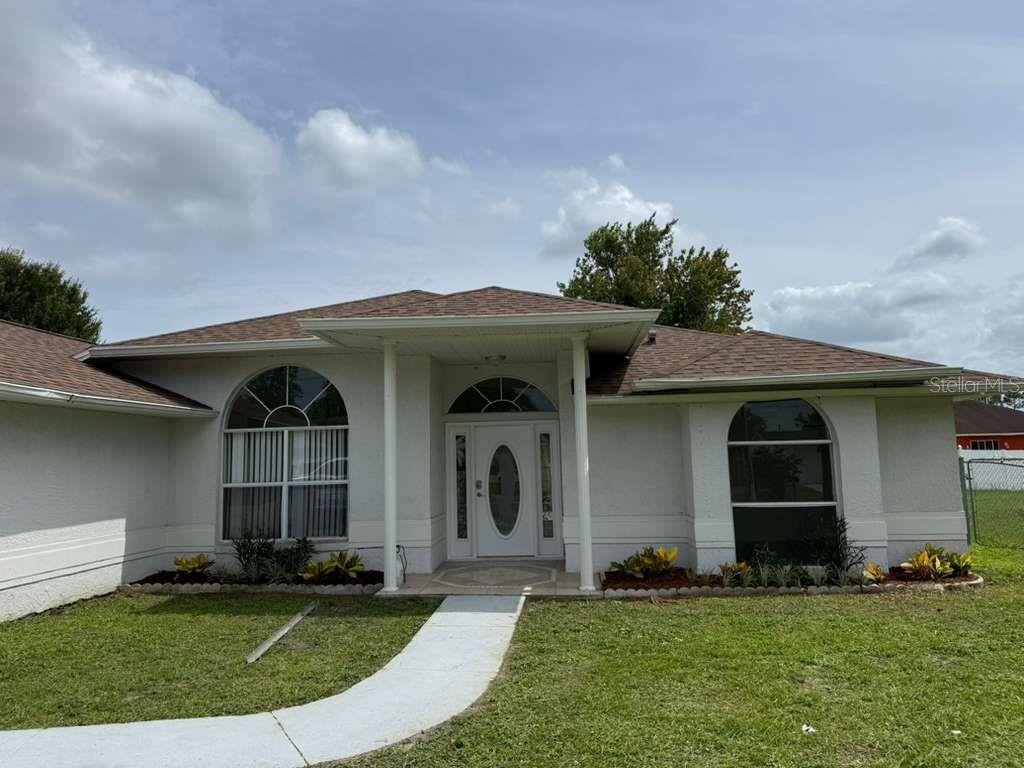 A single-story suburban house with a two-car garage, arched windows, and a grassy front lawn — 657 MCKINLEY COURT, KISSIMMEE, FL