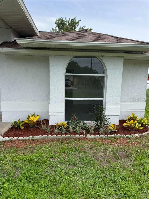 A living area with light wood-look flooring, a kitchen peninsula, and a sliding glass door — 657 MCKINLEY COURT, KISSIMMEE, FL