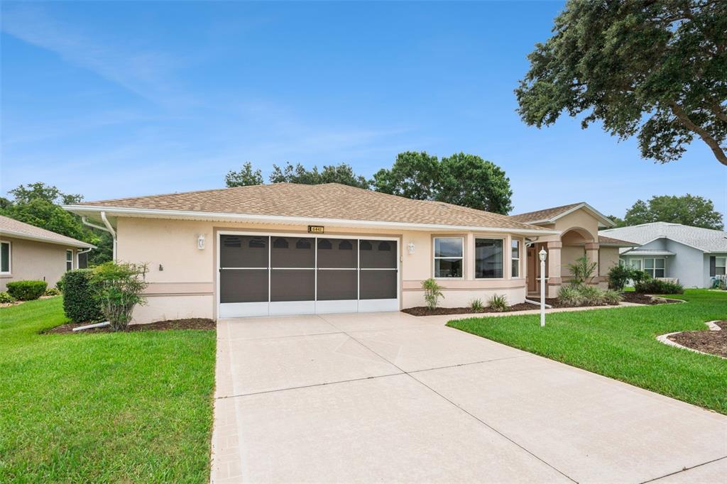 A single-story house with a beige exterior, a two-car garage, and a concrete driveway — 6441 WILANDER STREET, LEESBURG, FL