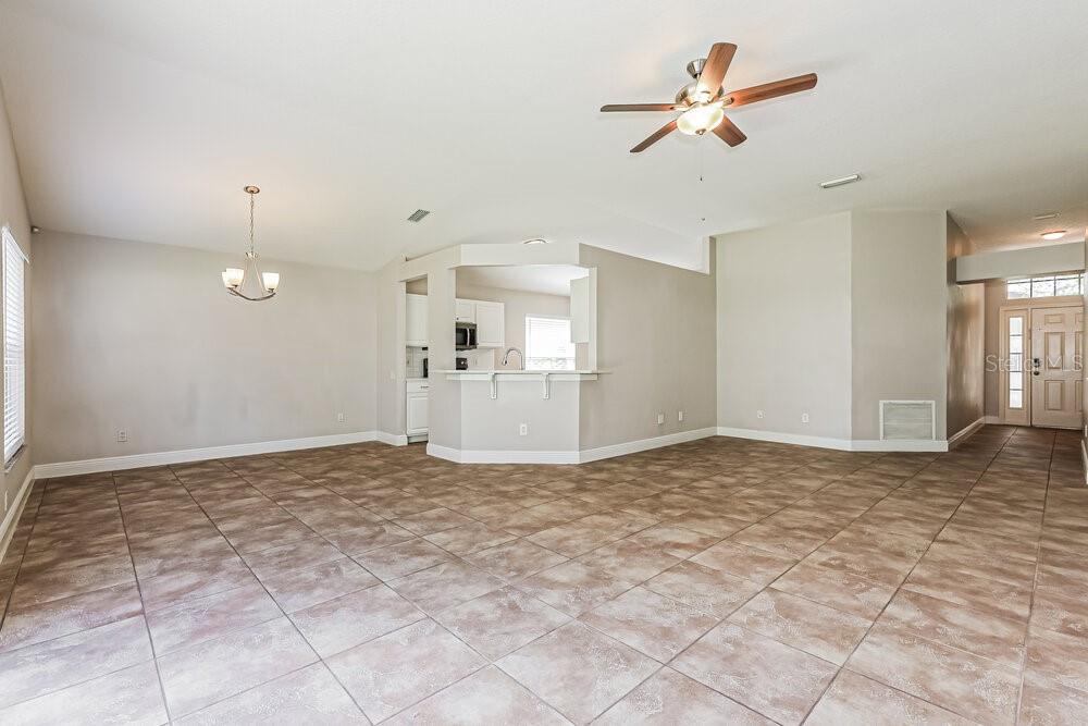 An open-concept living and dining area features neutral walls, tile flooring, and a ceiling fan — 10428 HUNTERS HAVEN BOULEVARD, RIVERVIEW, FL