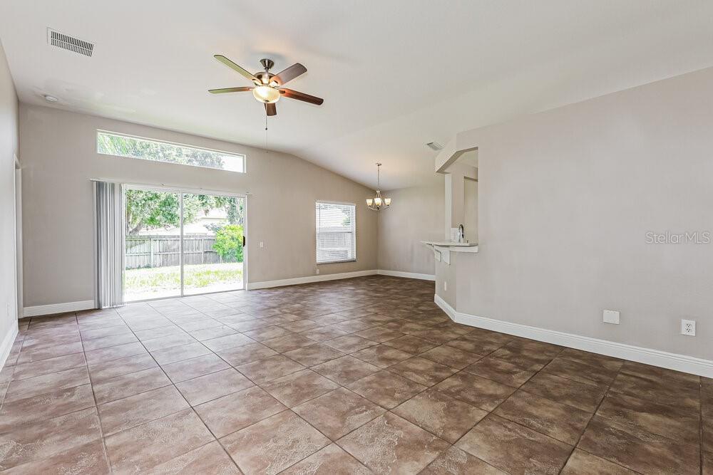 An open-concept living area features light-colored walls, tile flooring, a ceiling fan, and sliding doors — 10428 HUNTERS HAVEN BOULEVARD, RIVERVIEW, FL