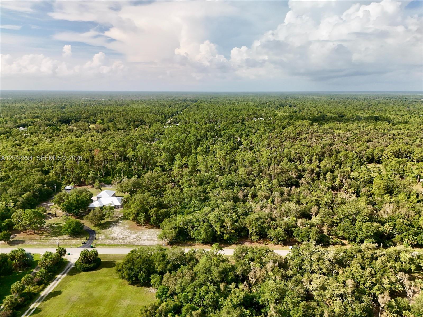 An aerial view shows a house surrounded by dense forest and a paved road — 280 35TH AVE NW, Naples FL 34120, NAPLES, FL