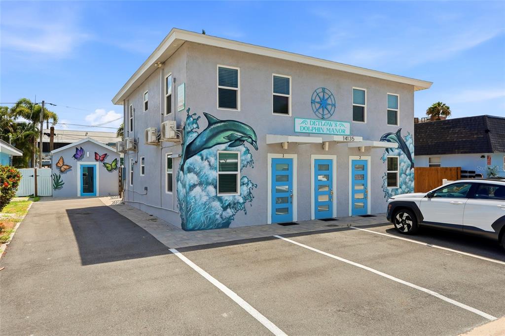 A two-story building with a dolphin mural, blue doors, and a paved parking lot — 14135 PALM STREET, MADEIRA BEACH, FL