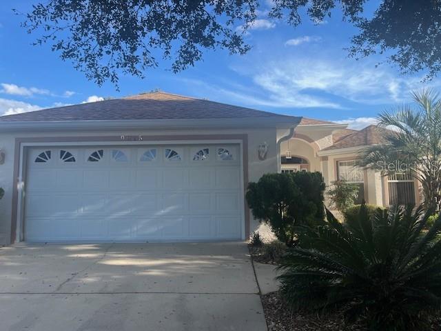 A single-story house features a two-car garage and a landscaped front yard under a blue sky — 9015 SW 96TH TERRACE, OCALA, FL
