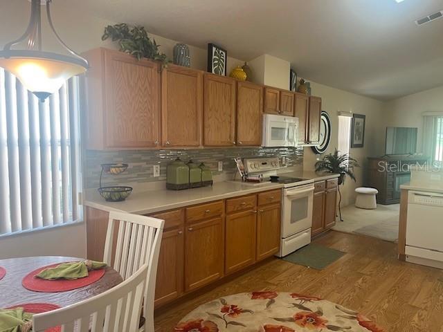 A kitchen with wood cabinets, light countertops, and a dining area with a round table — 9015 SW 96TH TERRACE, OCALA, FL
