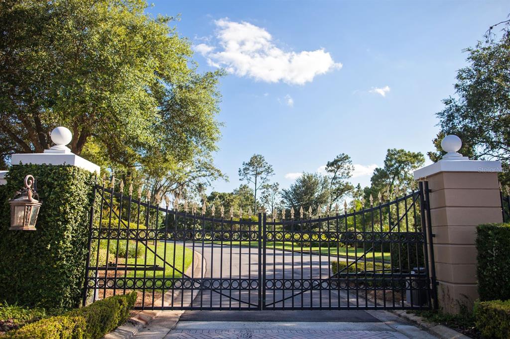 A black metal gate stands between two stone pillars topped with white spheres — 11091 CROMWELL ROAD, ORLANDO, FL