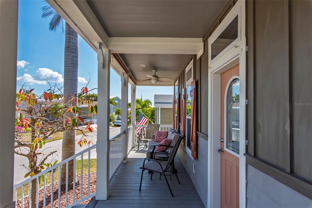 A covered porch features a ceiling fan, outdoor seating, and a peach-colored front door — 25 ALLIGATOR AVENUE, PUNTA GORDA, FL