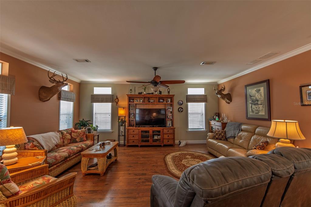 A living room features wood flooring, a wooden entertainment center, two sofas, and deer mounts — 25 ALLIGATOR AVENUE, PUNTA GORDA, FL
