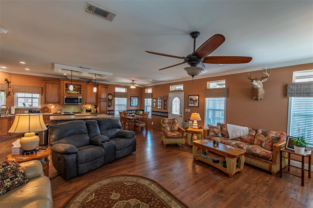 A living room and kitchen area with wood floors, brown walls, and a ceiling fan — 25 ALLIGATOR AVENUE, PUNTA GORDA, FL