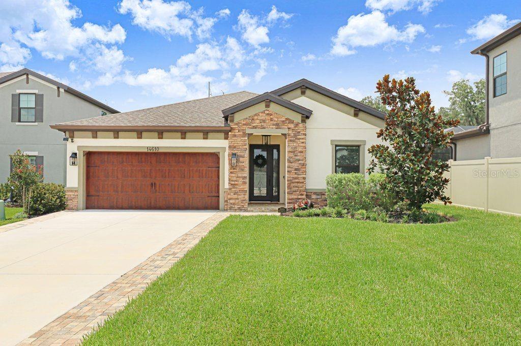 A single-story suburban house features a stone-accented entryway, a two-car garage, and a front lawn — 14610 HORSE TROT ROAD, LITHIA, FL