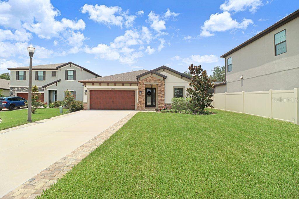 A single-story house with a two-car garage and a paved driveway under a blue sky — 14610 HORSE TROT ROAD, LITHIA, FL