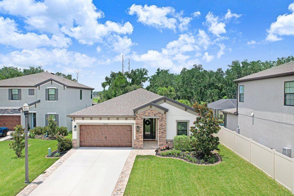 A single-story house with a stone facade, a two-car garage, and a paved driveway — 14610 HORSE TROT ROAD, LITHIA, FL